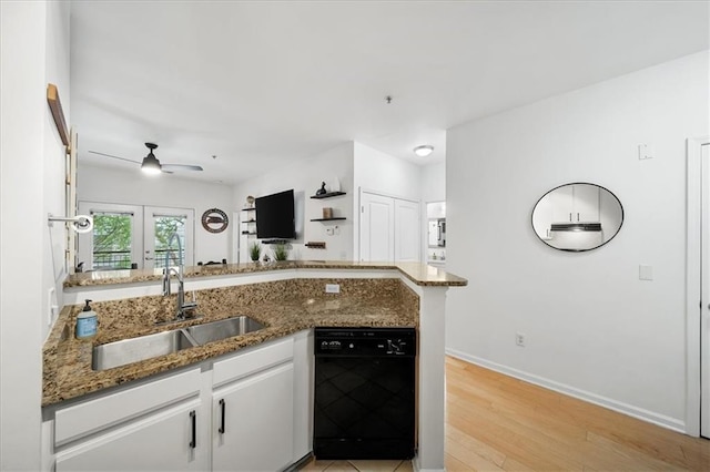 kitchen with white cabinetry, a sink, dark stone countertops, light wood-type flooring, and dishwasher