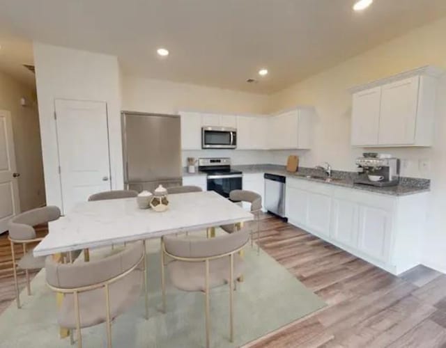 305 Winston Way, Villa Rica, GA 30180 - kitchen featuring appliances with stainless steel finishes, white cabinetry, a sink, light wood finished floors, and recessed lighting