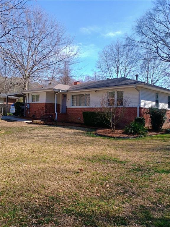 ranch-style house featuring a carport, brick siding, and a front yard