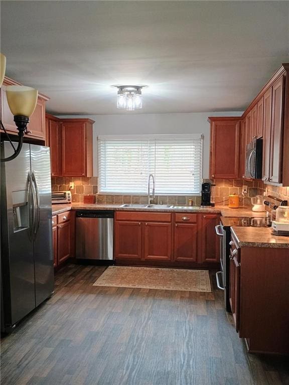 kitchen with stainless steel appliances, dark wood-type flooring, a sink, and tasteful backsplash