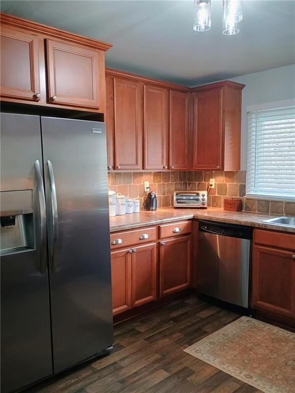 kitchen with a sink, appliances with stainless steel finishes, backsplash, and dark wood-style flooring