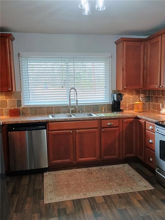 kitchen with dark wood-style floors, appliances with stainless steel finishes, decorative backsplash, and a sink