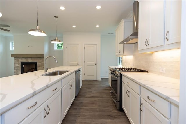 kitchen featuring sink, appliances with stainless steel finishes, light stone countertops, white cabinets, and wall chimney exhaust hood