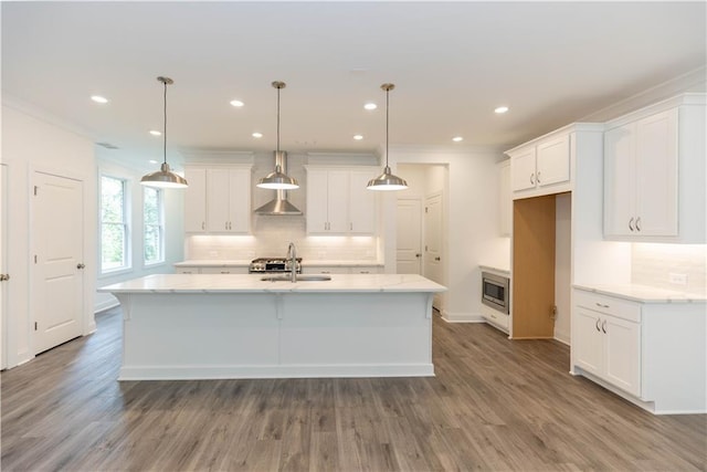 kitchen featuring a kitchen island with sink, white cabinetry, and decorative light fixtures