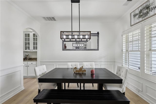 dining area with crown molding and light hardwood / wood-style floors