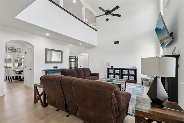 living room featuring a towering ceiling, ceiling fan, and light hardwood / wood-style flooring