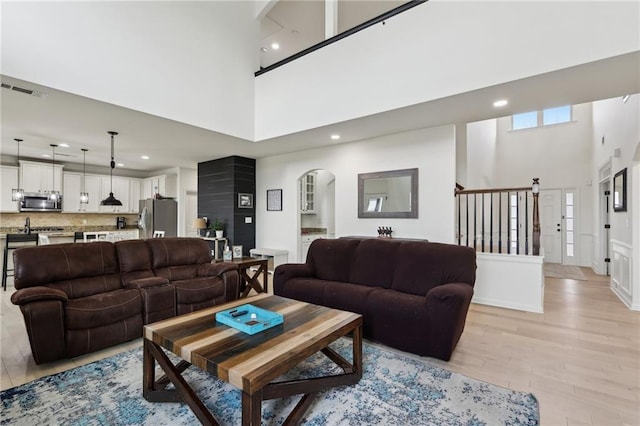 living room featuring a towering ceiling and light wood-type flooring