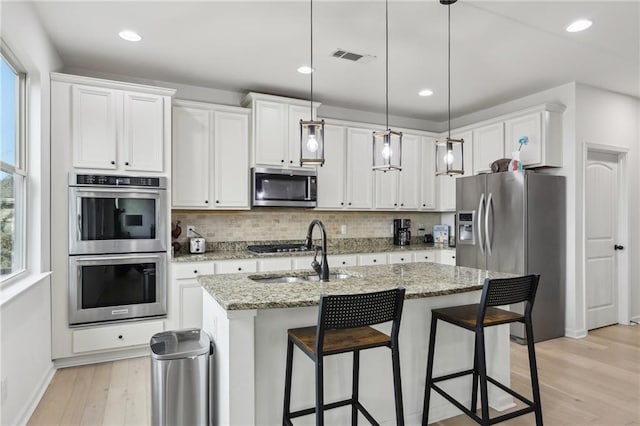 kitchen with white cabinetry, pendant lighting, an island with sink, and appliances with stainless steel finishes