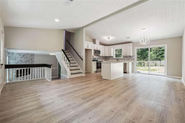 interior space featuring white cabinets, vaulted ceiling, light hardwood / wood-style floors, and backsplash