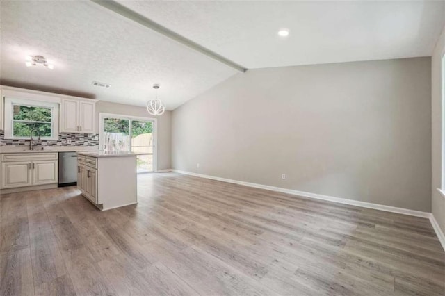 kitchen featuring decorative backsplash, light hardwood / wood-style floors, dishwasher, pendant lighting, and lofted ceiling