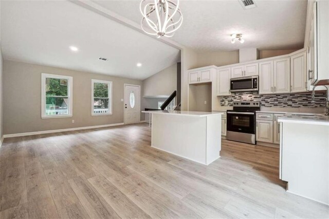 kitchen with appliances with stainless steel finishes, light hardwood / wood-style flooring, decorative light fixtures, decorative backsplash, and a center island