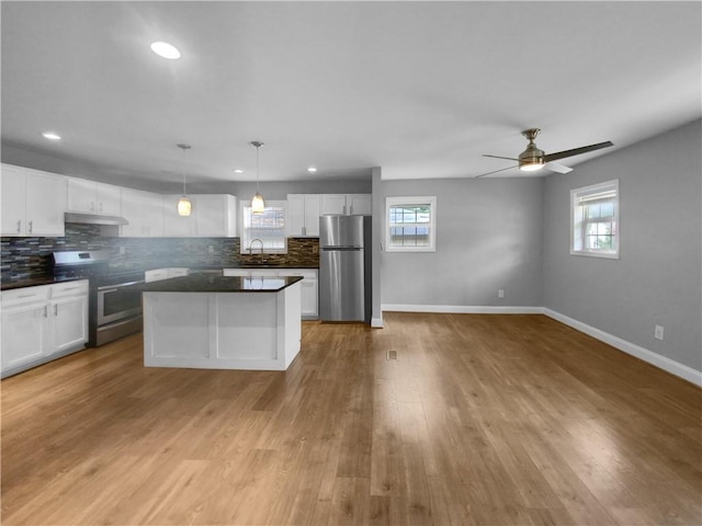 kitchen with white cabinetry, hanging light fixtures, appliances with stainless steel finishes, and a kitchen island