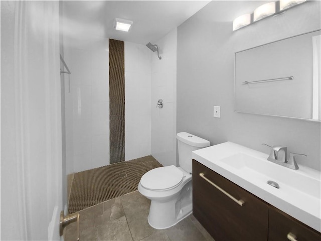 bathroom with toilet, vanity, and a tile shower