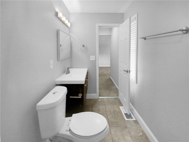 bathroom with toilet, vanity, and tile patterned floors