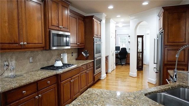 kitchen with light stone counters, stainless steel appliances, and backsplash