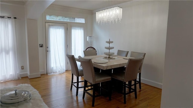 dining room with an inviting chandelier, ornamental molding, and light hardwood / wood-style floors