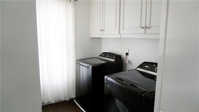 clothes washing area with dark tile patterned floors, separate washer and dryer, and cabinets