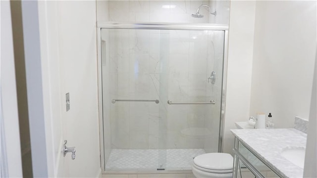 bathroom featuring toilet, vanity, and a shower with shower door