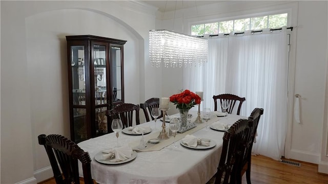 dining room with hardwood / wood-style floors, an inviting chandelier, and ornamental molding