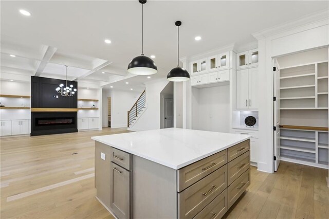 kitchen with a center island, beamed ceiling, coffered ceiling, hanging light fixtures, and white cabinets