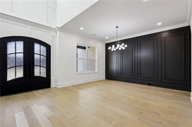 entrance foyer with a chandelier, crown molding, light hardwood / wood-style flooring, and french doors