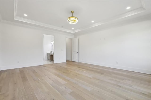 interior space featuring crown molding, a tray ceiling, and light hardwood / wood-style flooring