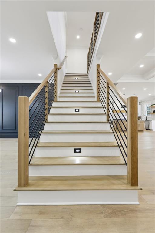 stairs with wood-type flooring and crown molding