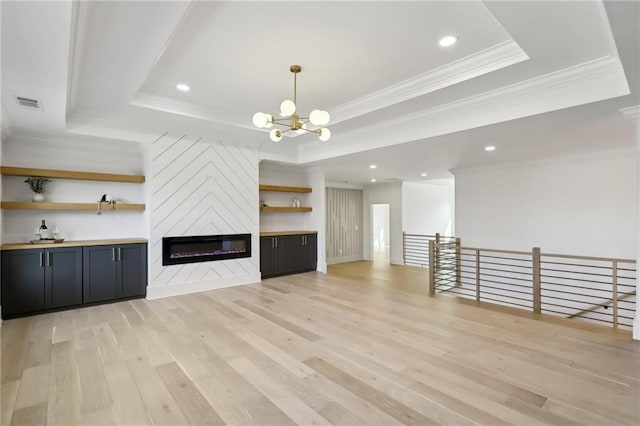 unfurnished living room featuring a fireplace, light hardwood / wood-style floors, ornamental molding, a chandelier, and a tray ceiling