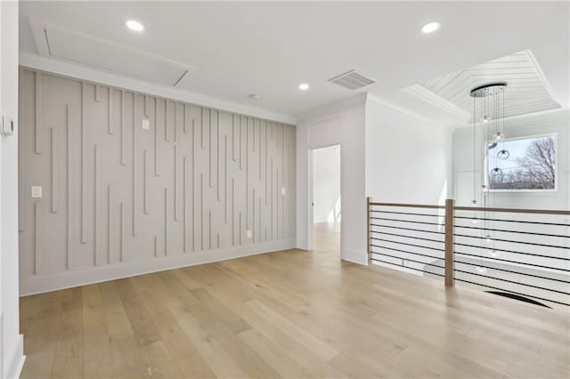 spare room with ornamental molding and light hardwood / wood-style floors