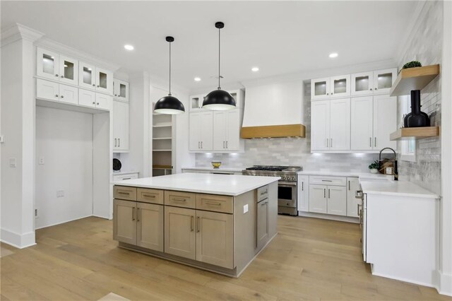 kitchen with a kitchen island, custom exhaust hood, white cabinetry, decorative backsplash, and stainless steel stove