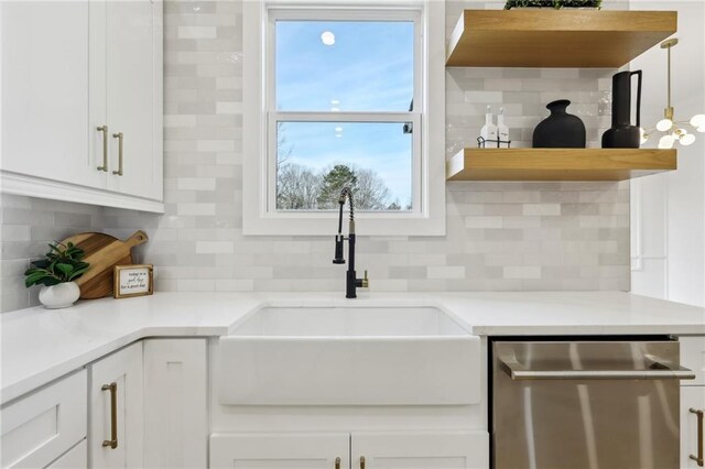 kitchen featuring stainless steel dishwasher, white cabinets, tasteful backsplash, and sink