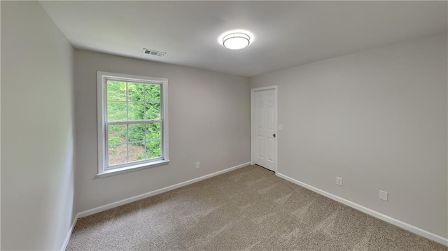 carpeted spare room with visible vents and baseboards
