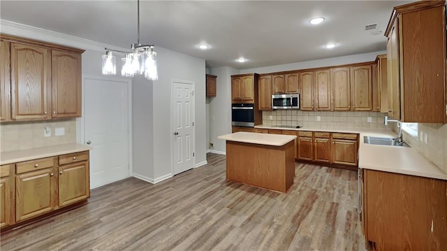kitchen featuring a sink, brown cabinets, stainless steel appliances, light wood-type flooring, and tasteful backsplash