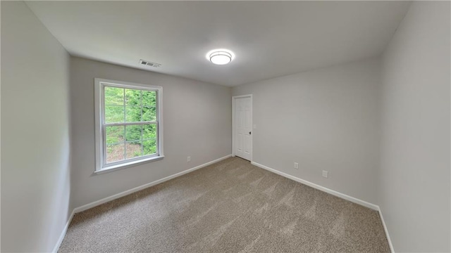 unfurnished room featuring visible vents, light carpet, and baseboards