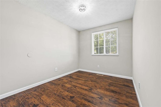 spare room featuring dark wood-type flooring and a textured ceiling