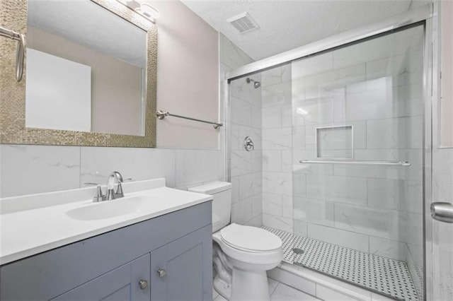 bathroom with toilet, a shower with shower door, a textured ceiling, tile walls, and vanity