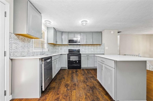 kitchen with appliances with stainless steel finishes, decorative backsplash, sink, and gray cabinetry