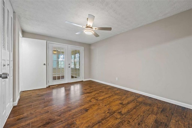 empty room featuring ceiling fan, dark wood-type flooring, french doors, and a textured ceiling