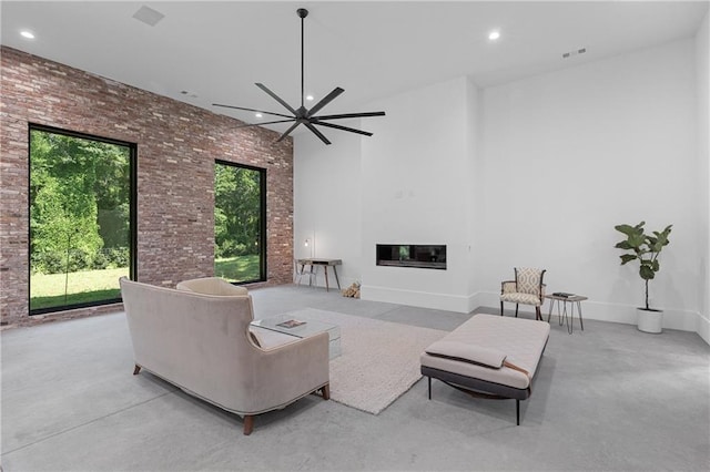 538 Main St, Palmetto, GA 30268 - living area featuring brick wall, a ceiling fan, a glass covered fireplace, a high ceiling, and finished concrete floors