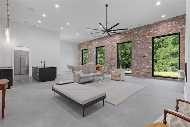 538 Main St, Palmetto, GA 30268 - living room featuring a high ceiling, finished concrete floors, brick wall, recessed lighting, and ceiling fan