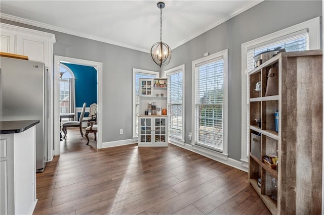 dining room with a chandelier, dark wood-type flooring, healthy amount of natural light, and crown molding