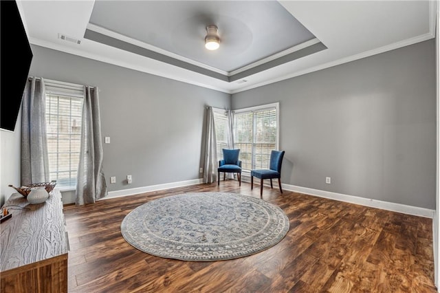 living area with ornamental molding, wood finished floors, a raised ceiling, and baseboards