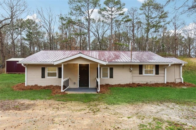 ranch-style house with concrete block siding, a front yard, and metal roof