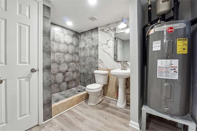 full bath featuring visible vents, toilet, water heater, a tile shower, and wood finished floors