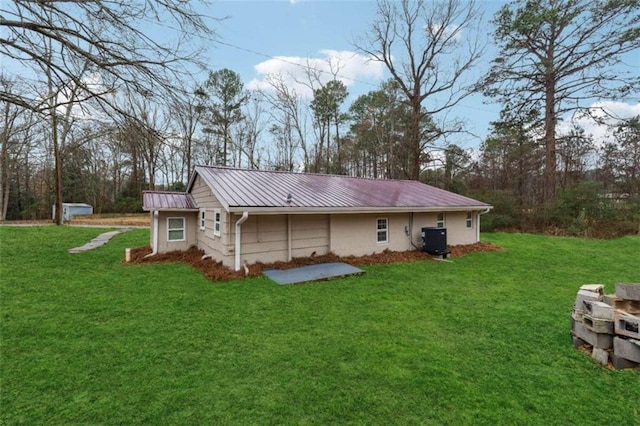 exterior space featuring a standing seam roof, cooling unit, a yard, and metal roof