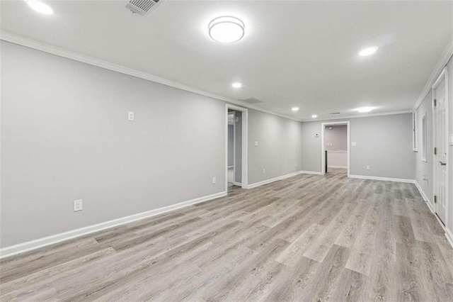 finished below grade area featuring visible vents, baseboards, light wood finished floors, and ornamental molding