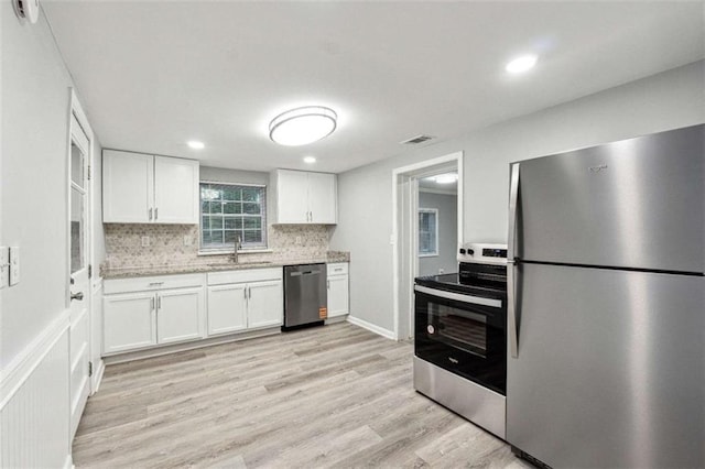 kitchen with visible vents, light wood-style flooring, a sink, stainless steel appliances, and white cabinets