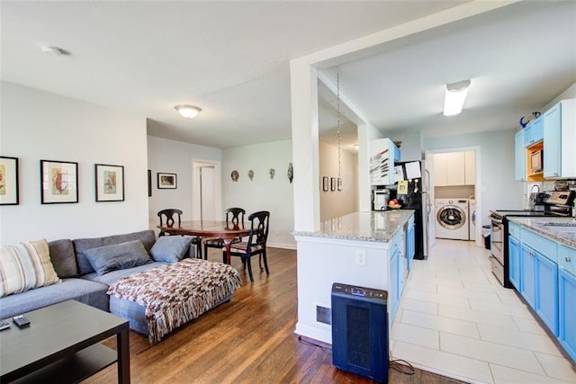 kitchen featuring blue cabinets, stainless steel appliances, a kitchen island, open floor plan, and independent washer and dryer