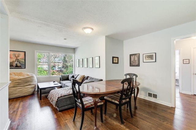 dining space with visible vents, dark wood finished floors, and baseboards