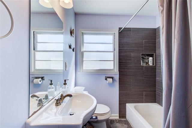 bathroom with shower / bath combo, a sink, toilet, and baseboards